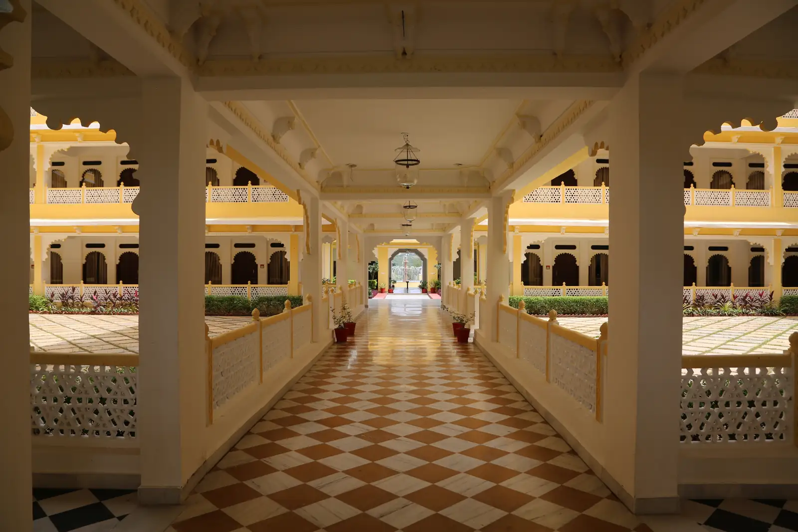 Checkered marble corridor at Sinclairs Palace Retreat Udaipur, opening onto the fountain courtyard