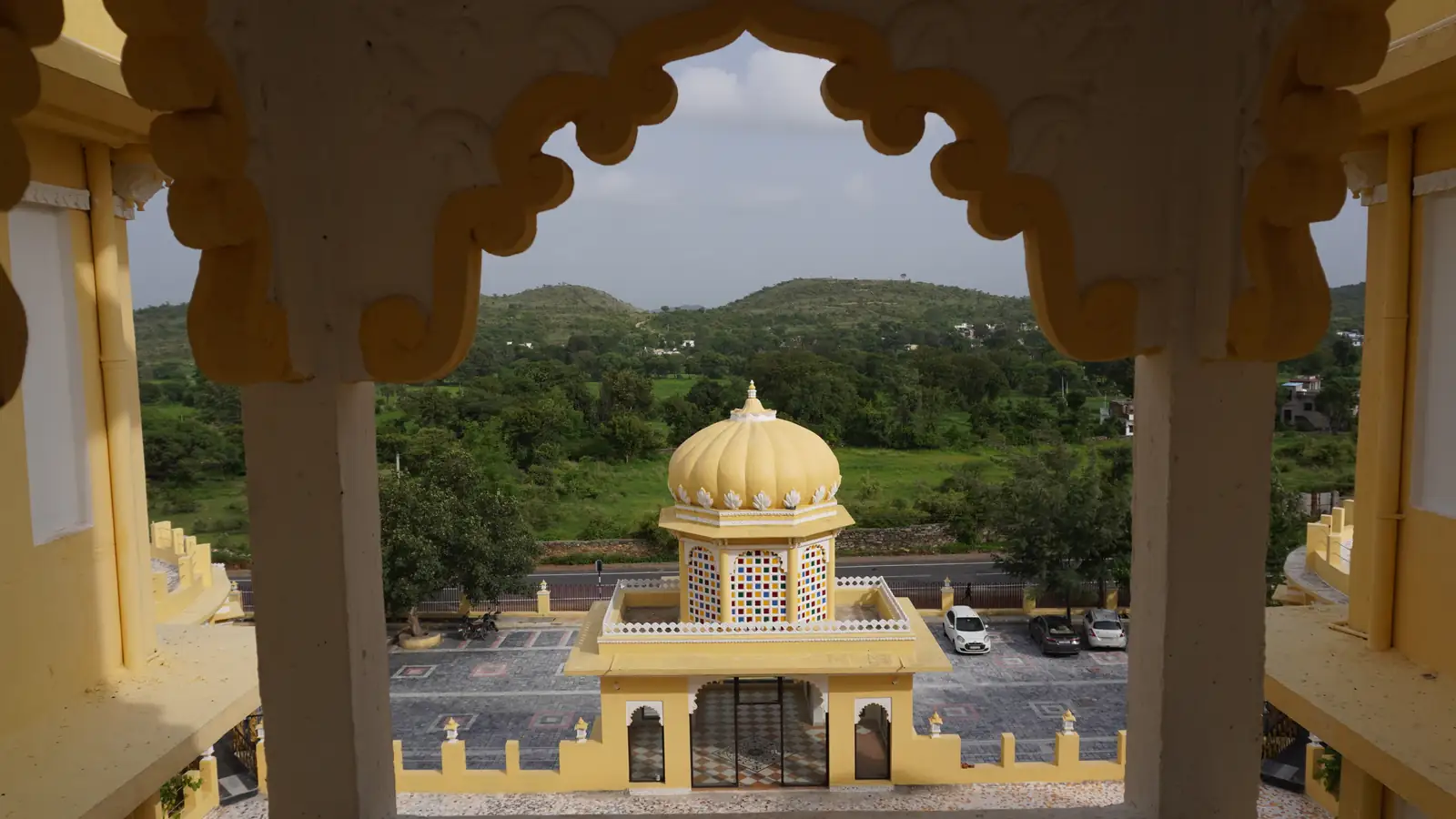 View of a domed pavilion framed by an archway, with the Haldighati hills beyond